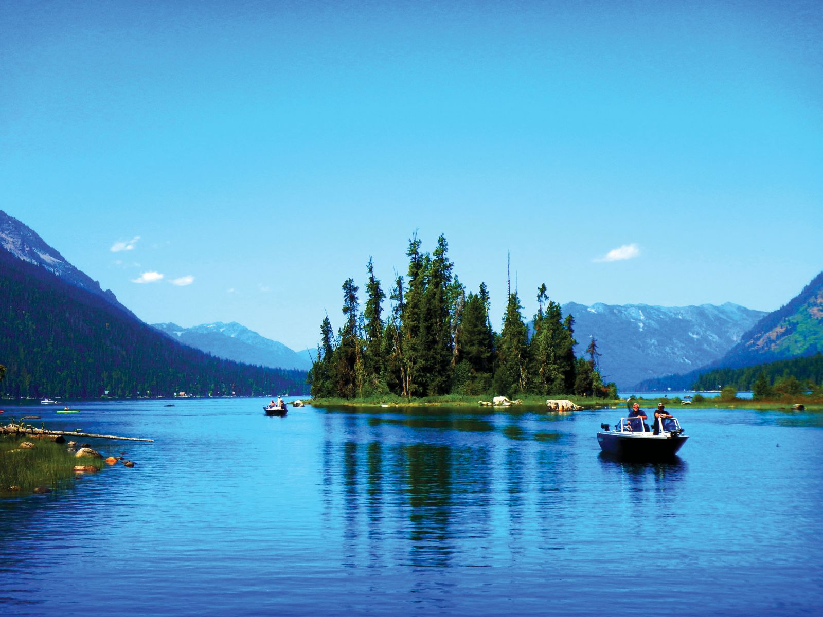 Anglers returning from sockeye fishing on Lake Wenatchee, showcasing a boat on the lake with fishermen holding their catches.